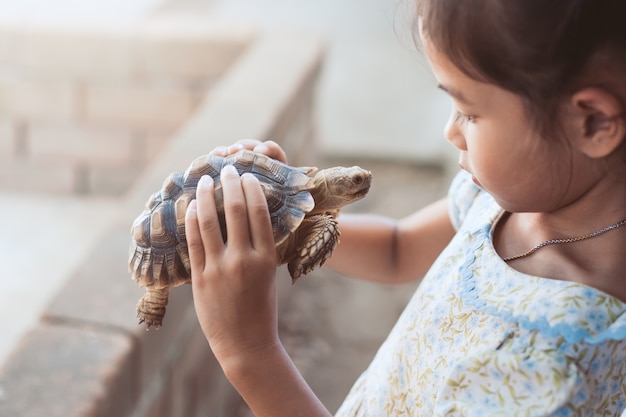 Premium Photo | Cute asian child girl holding and playing with turtle