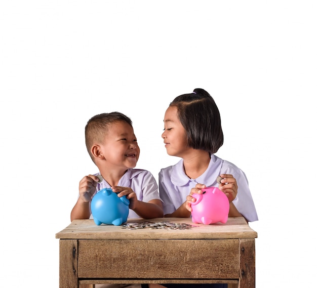 Cute asian country boy and girl putting coins into piggy bank isolated on white background Premium Photo