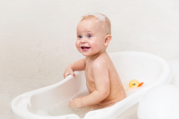 Cute baby boy in the bathtub with ballons and duck. | Premium Photo