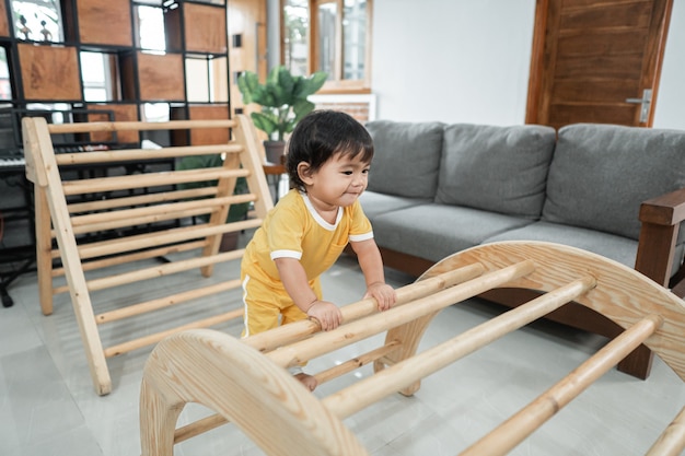 Premium Photo Cute Baby Climbing On Pikler Triangle Toys In The Living Room