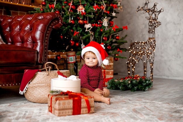 Premium Photo | Cute baby santa sits at home near the christmas tree ...