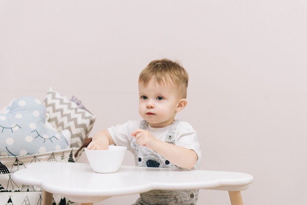 テーブルに座って食べているかわいい赤ちゃん プレミアム写真