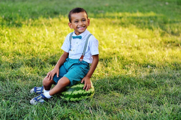 巨大なスイカの上に座っていると公園に笑顔かわいい黒人のアフリカ系アメリカ人の少年 プレミアム写真