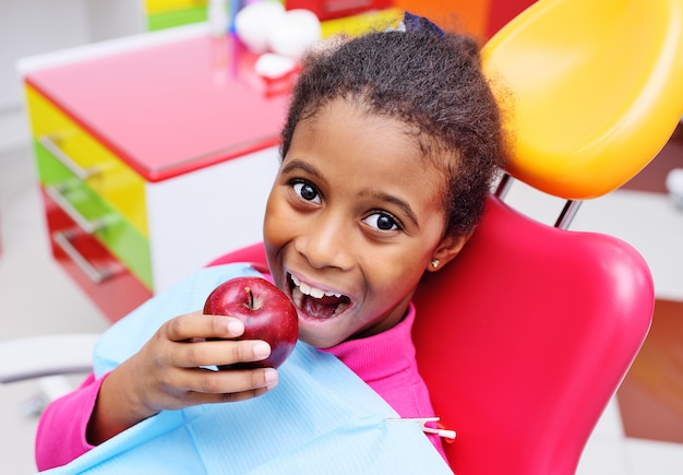 かわいい黒いアフリカ系アメリカ人の女の子子供笑顔と熟した赤いリンゴを食べる プレミアム写真