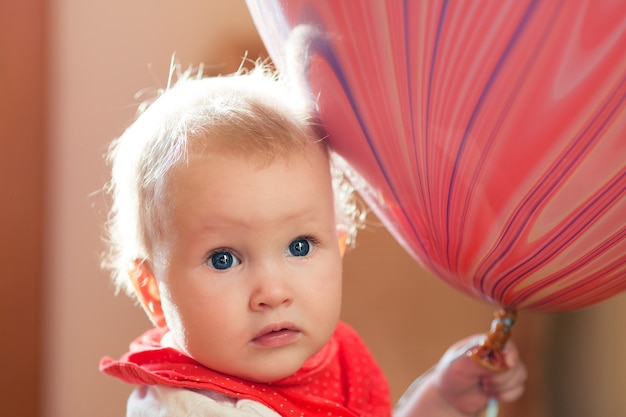 大きなピンクの風船を保つ青い目を持つかわいい金髪の赤ちゃん プレミアム写真