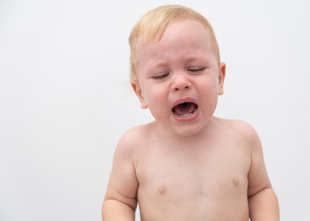 白い壁で泣いているかわいい金髪の赤ちゃん幼児男の子 プレミアム写真