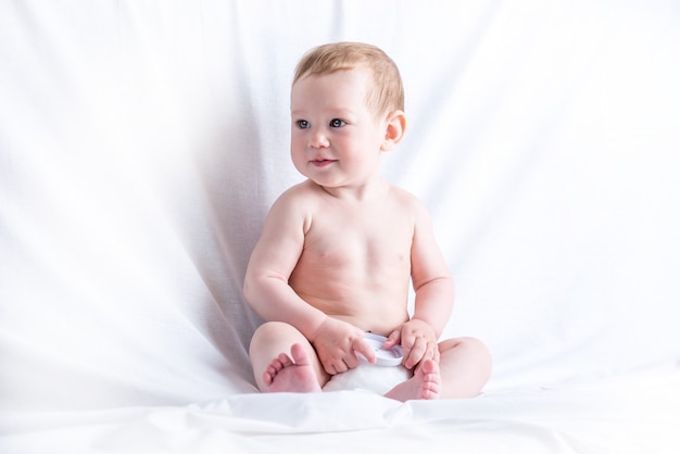 Cute blue-eyed baby 6-9 months smiling and playing on white background. children's emotions Premium Photo