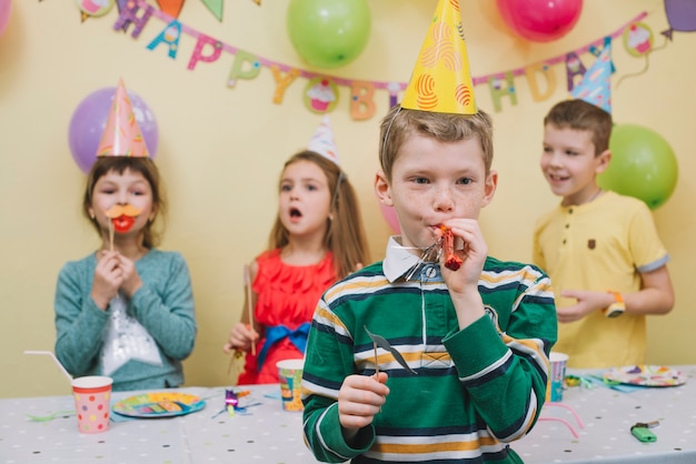 Free Photo | Cute boy blowing noisemaker on birthday party