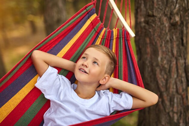 Premium Photo | Cute boy is lying in a colorful hammock. the kid is ...