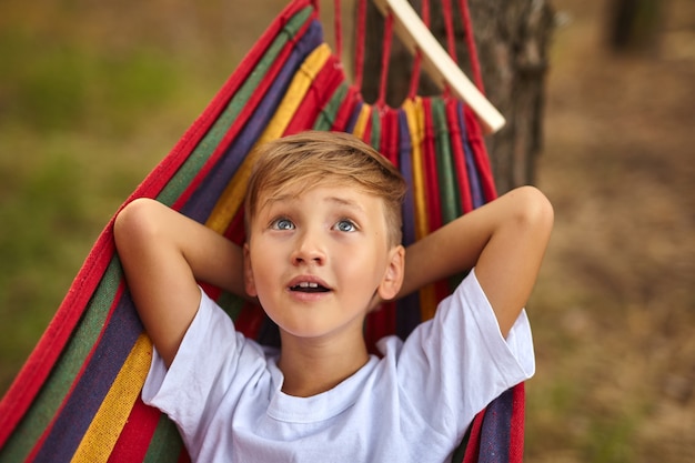 Premium Photo | Cute boy is lying in a colorful hammock. the kid is ...