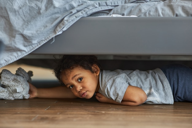 Premium Photo Cute Boy Peeking Out From Under The Bed