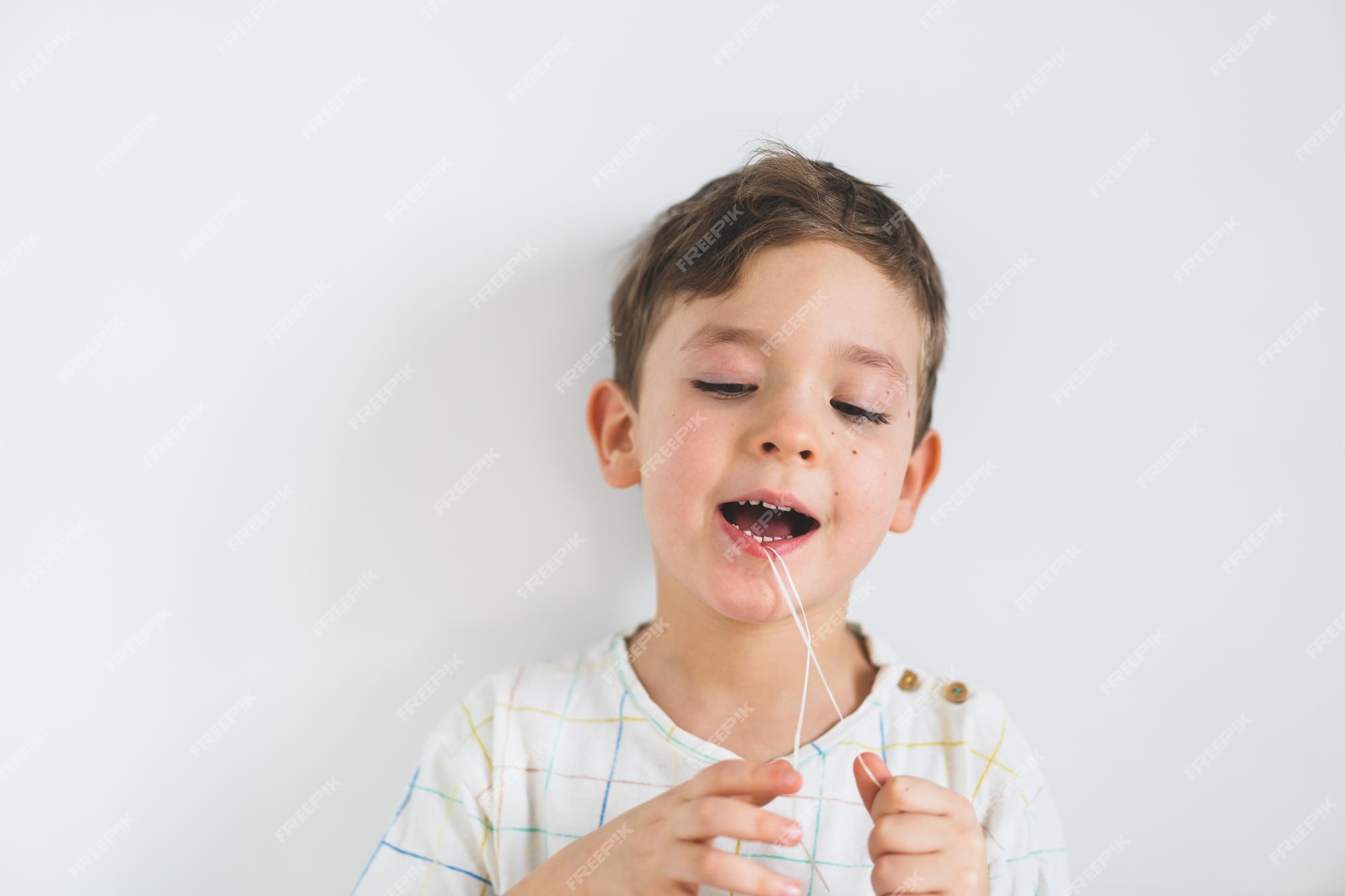 Premium Photo | Cute boy pulling loose tooth using a dental floss. the ...