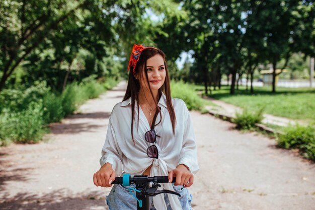 Premium Photo | Cute brunette girl rides on an electrode scooter in the ...