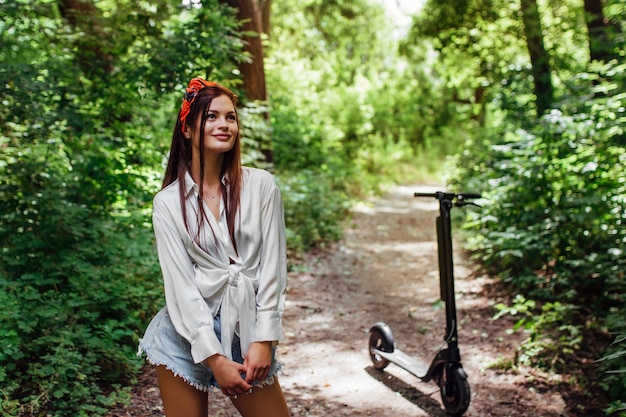 Premium Photo | Cute brunette girl rides on an electrode scooter in the ...