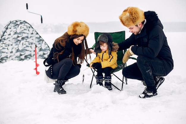 Cute family sitting on a winter fishing with little son Free Photo