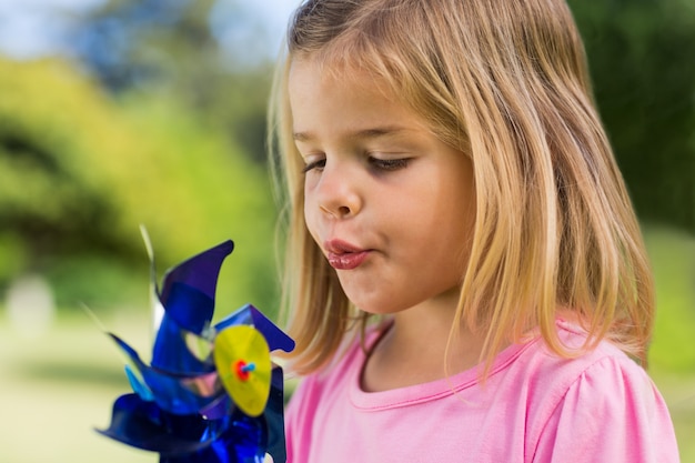 Premium Photo | Cute girl blowing pinwheel at park