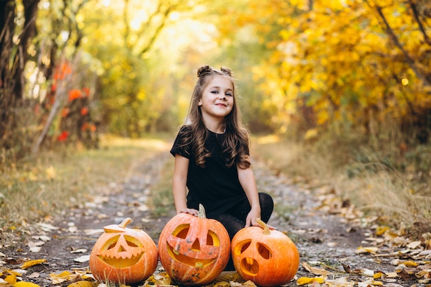 Cute girl dressed in halloween costume outdoors with pumpkins Free Photo