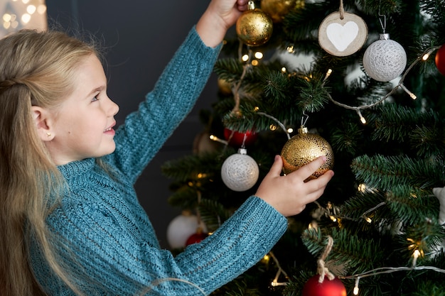 Free Photo | Cute girl hanging decorations on christmas tree