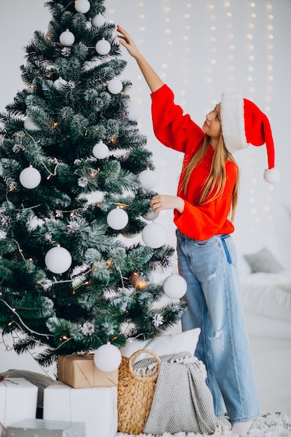 Free Photo | Cute girl teenager in red santa hat by christmas tree