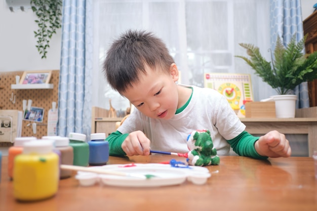 かわいい幸せな小さなアジア人3 4歳の幼児の男の子の子供がdiy石膏絵画おもちゃに色を塗る 自宅で3d石膏像 子供と幼児のコンセプトのための創造的な遊び 選択的な焦点 プレミアム写真