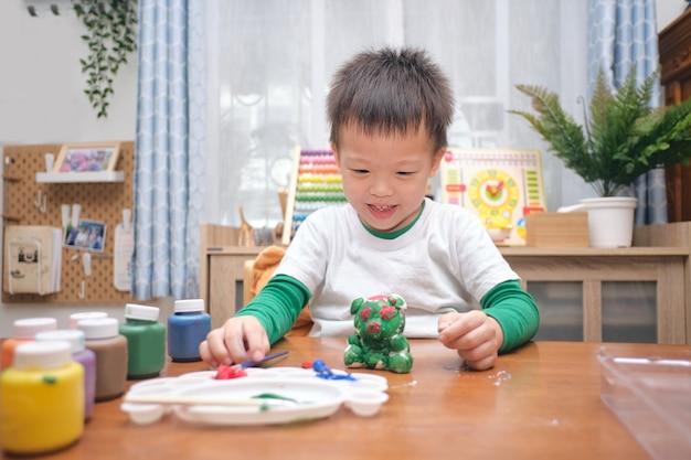 かわいい幸せな小さなアジア人3 4歳の幼児の男の子の子供がdiy石膏絵画おもちゃに色を塗る 自宅で3d石膏像 子供と幼児のコンセプトのための創造的な遊び 選択的な焦点 プレミアム写真