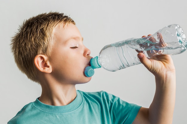 Cute kid drinking water from a plastic bottle Free Photo