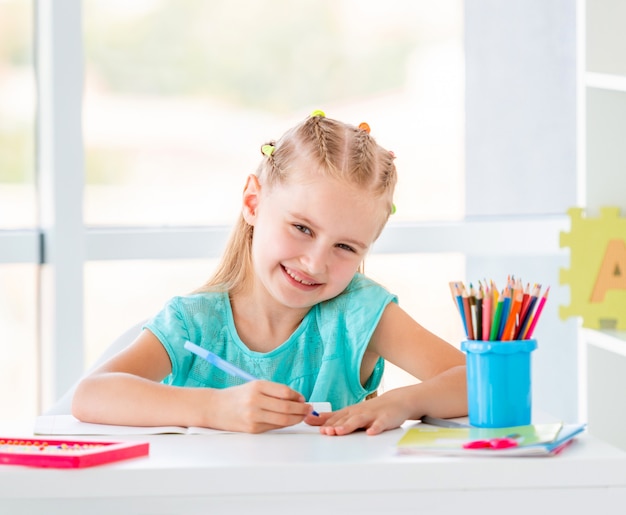 Cute Kid Girl Sitting At The Desk Coloring With Pencils Premium