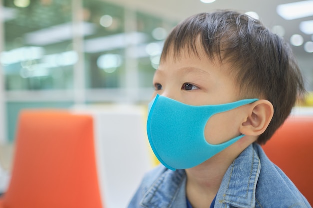 かわいい小さなアジア3 4歳幼児男の子子供pm 2 5大気汚染に対する保護医療マスクを身に着けている 子供が医者に会うのを待っているソファに座って プレミアム写真