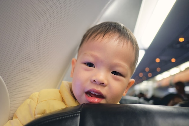 飛行機の飛行中に笑っているかわいい小さなアジアの3歳の幼児の男の子の子供 プレミアム写真