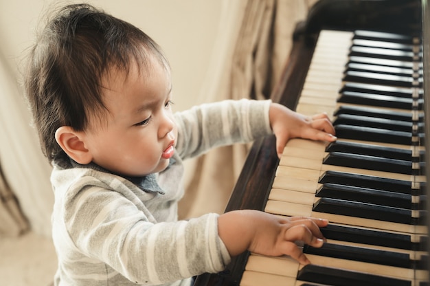 かわいい男の子は家でピアノを弾きます プレミアム写真