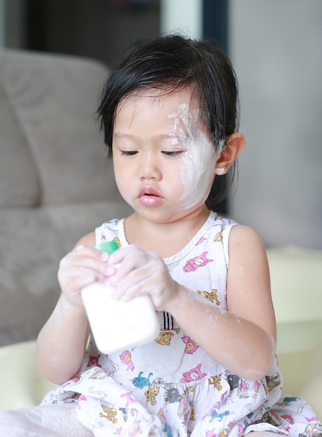 Premium Photo | Cute little baby girl applying baby powder on her face ...