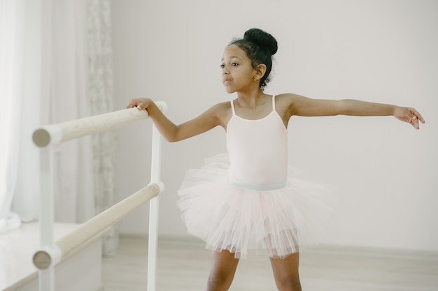 ピンクのバレエ衣装でかわいい小さなバレリーナ トウシューズを履いた子供が部屋で踊っています ダンスクラスの子供 無料の写真