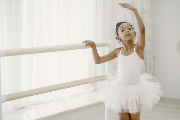 ピンクのバレエ衣装でかわいい小さなバレリーナ トウシューズを履いた子供が部屋で踊っています ダンスクラスの子供 無料の写真