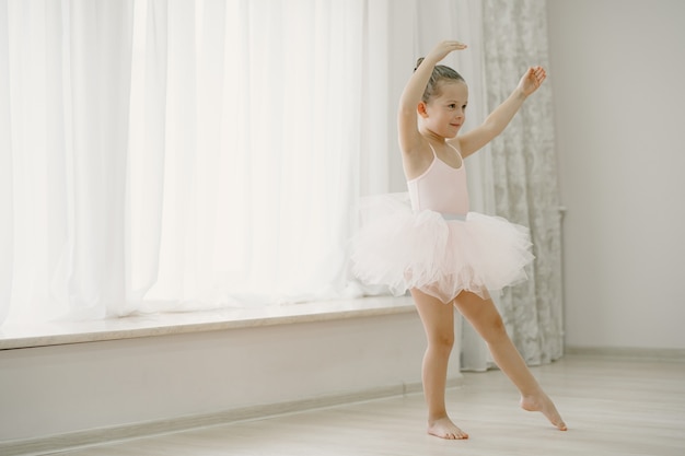 ピンクのバレエ衣装のかわいい小さなバレリーナ トウシューズを履いた子供が部屋で踊っています ダンスクラスの子供 無料の写真