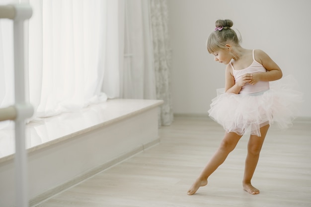ピンクのバレエ衣装のかわいい小さなバレリーナ トウシューズを履いた子供が部屋で踊っています ダンスクラスの子供 無料の写真