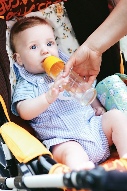 Cute little blue eyes baby boy with bottle in stroller