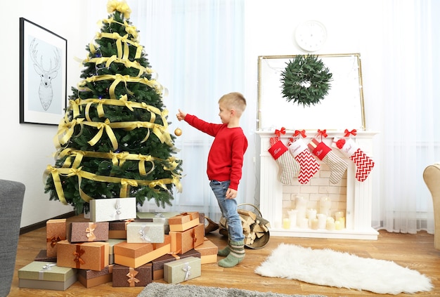 Premium Photo | Cute little boy decorating christmas tree at home