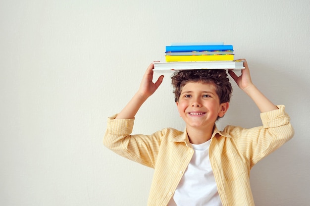 Premium Photo | Cute little boy holding many books on his head and smiling