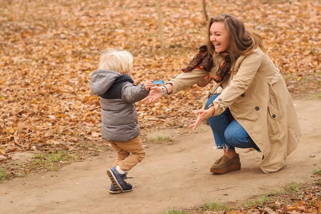 かわいい男の子が秋の公園で母親に駆け寄る プレミアム写真