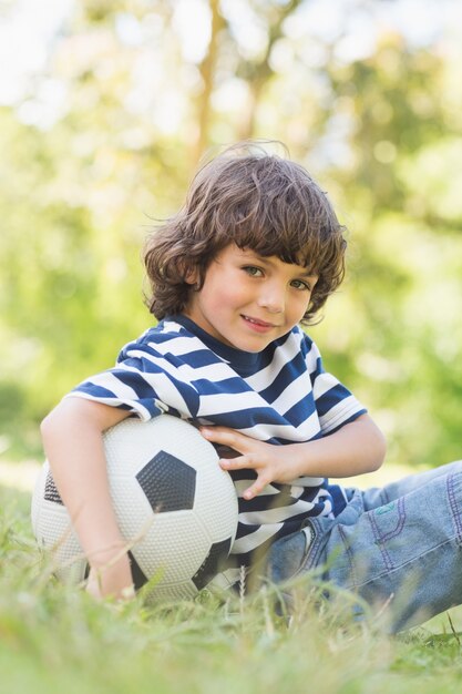 Premium Photo | Cute little boy with football sitting on grass in park