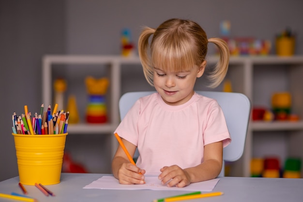 Premium Photo | Cute little child girl writing with pencils in day care ...