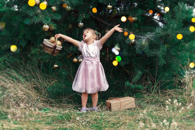 かわいい女の子がクリスマスツリーを飾ります 赤ちゃんは木の下で贈り物を見つけて幸せ プレミアム写真