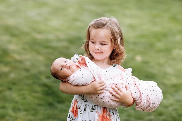 妹を屋外で抱っこするかわいい女の子 プレミアム写真