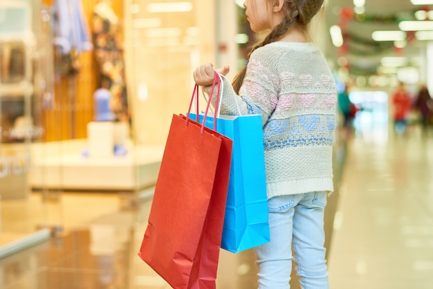 Premium Photo | Cute little girl holding shopping bags