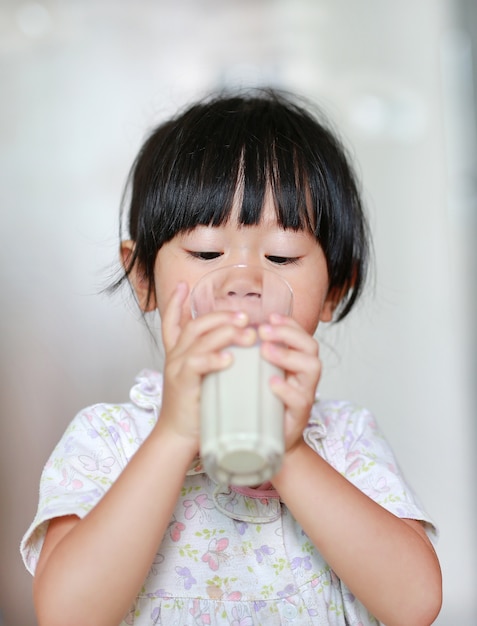 Cute Little girl in pajamas drinking milk from glass indoor at the morning. Premium Photo