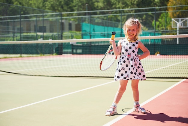 Free Photo | Cute little girl playing tennis on the tennis court outside.
