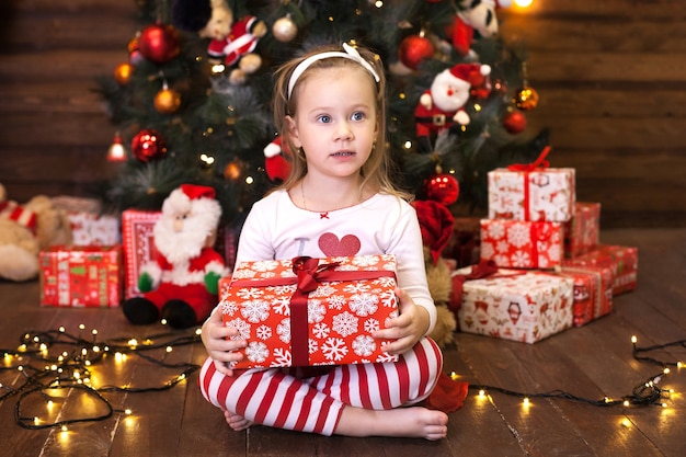 Premium Photo | Cute little girl in red striped pajamas sitting by ...