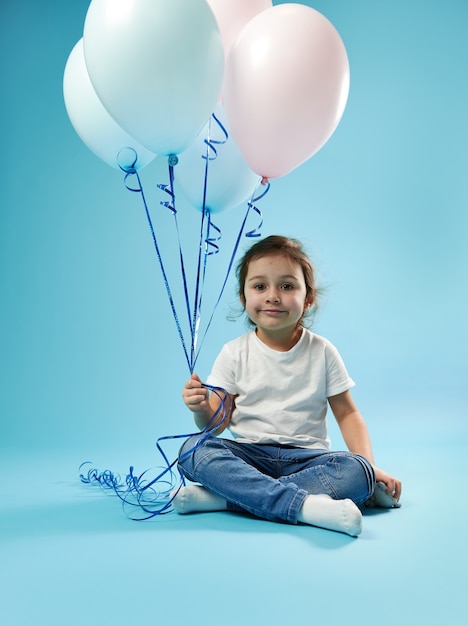 Premium Photo | Cute little girl sitting on blue surface ...