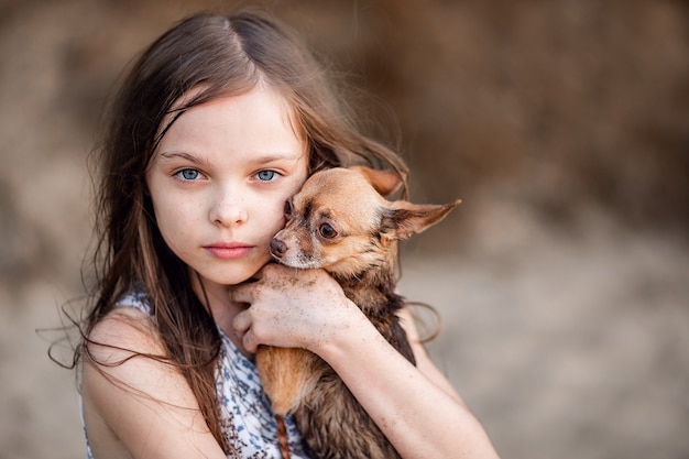 かわいい十代の少女は彼女の犬を抱きしめます チワワと子供の肖像画 髪の長い女の子はペットへの愛情と優しい 気持ちを示しています 飼い主の手にあるサラブレッド犬 プレミアム写真