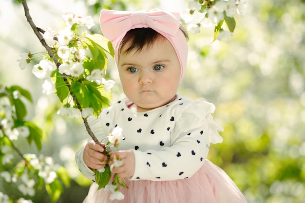 春に桜の枝を持っているかわいい生後6ヶ月の赤ちゃん プレミアム写真